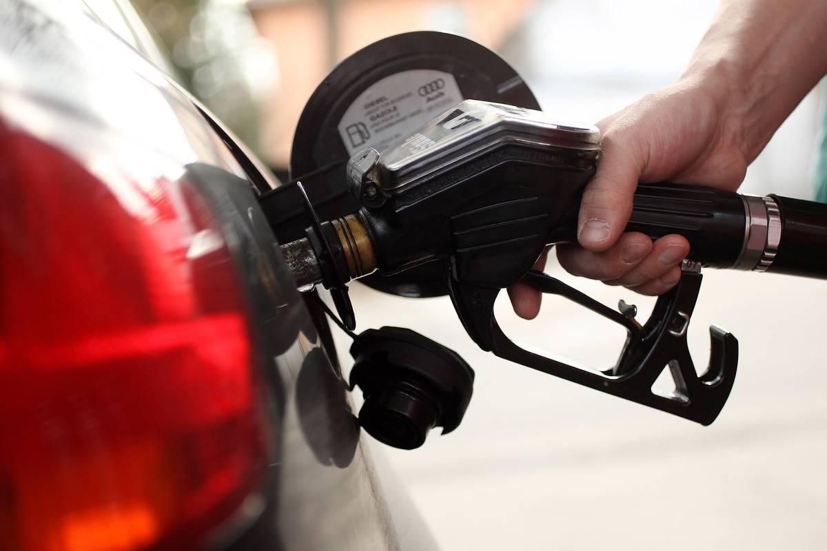 A gasoline station attendant pumps diesel into a car