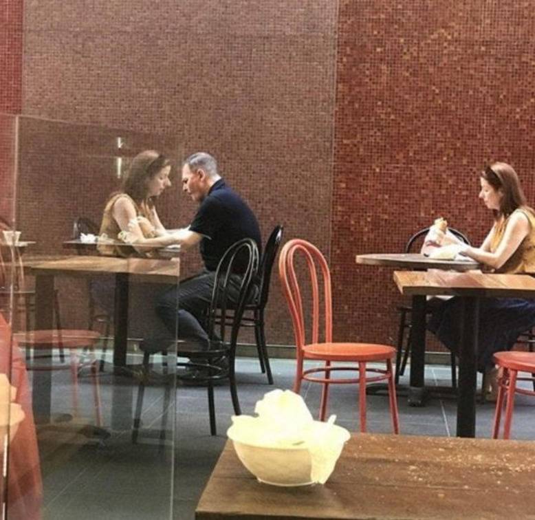 reflection on clear divider makes man and woman look like they're sitting together