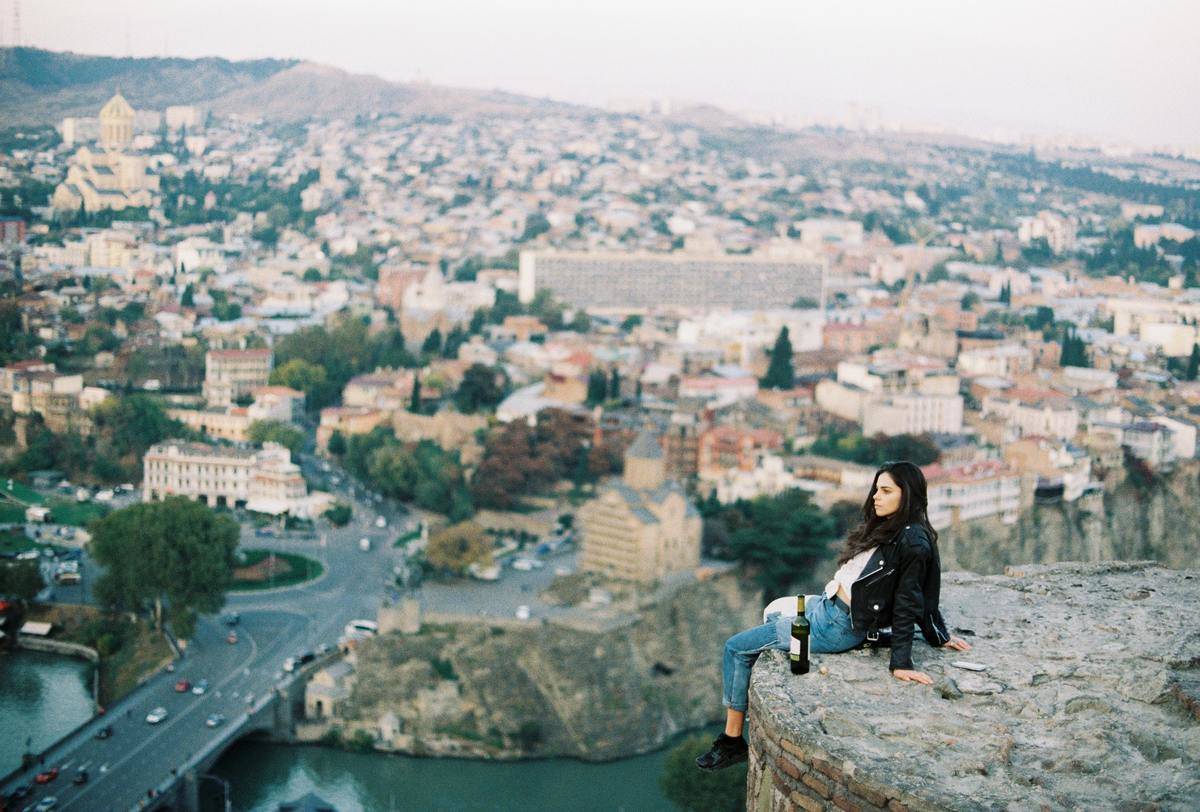 woman sitting on rock overlooking city
