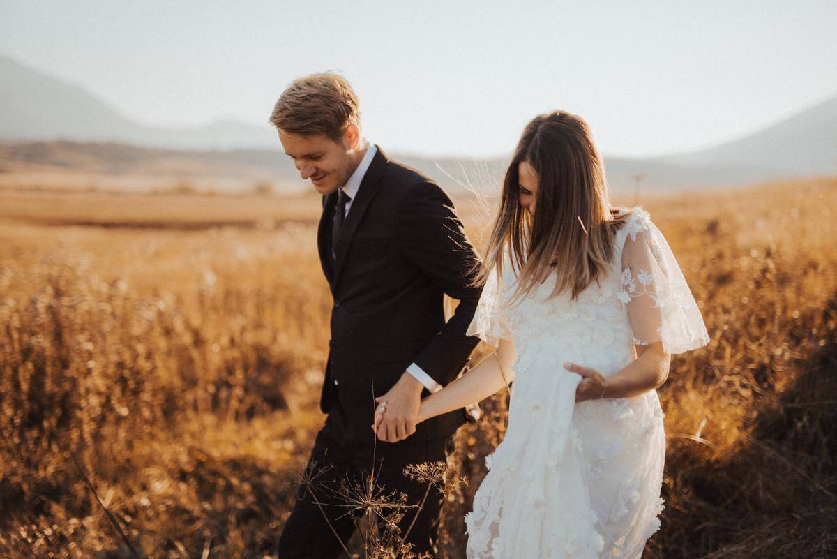 bride and groom walking through field