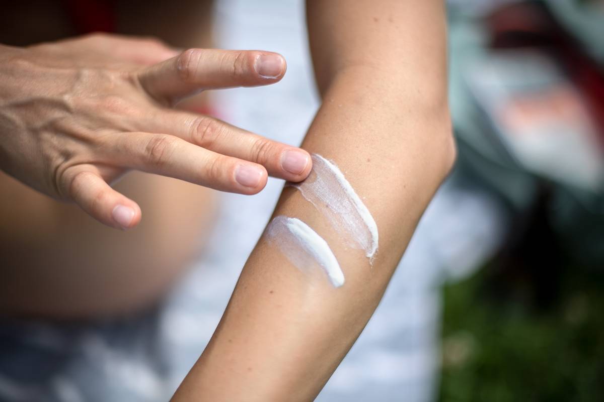 A person rubs two lines of sunscreen on her arm.