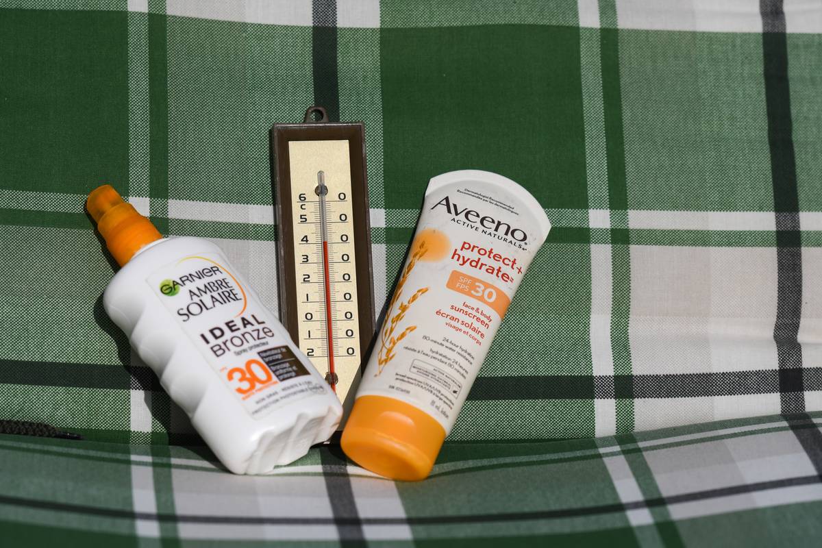 Sunscreen bottles and a thermometer close to 40 ° C sit on a chair.