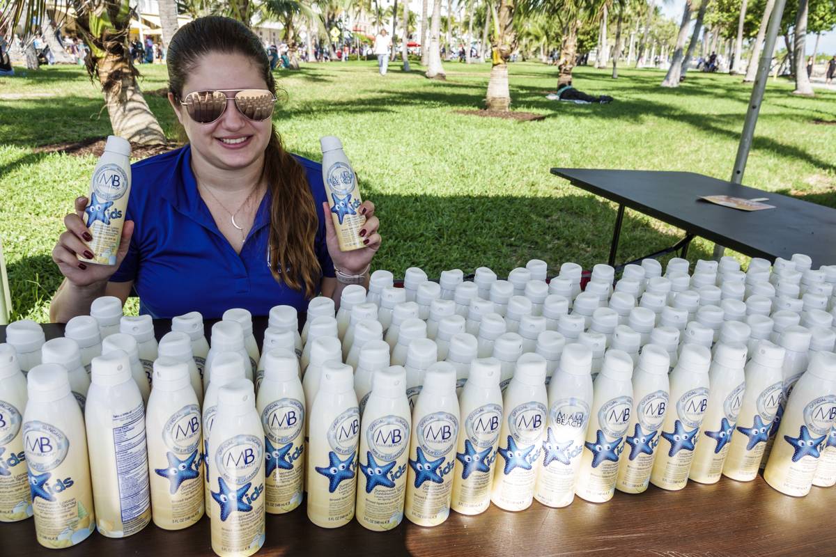 A woman hands out free sunscreen bottles at a parade.