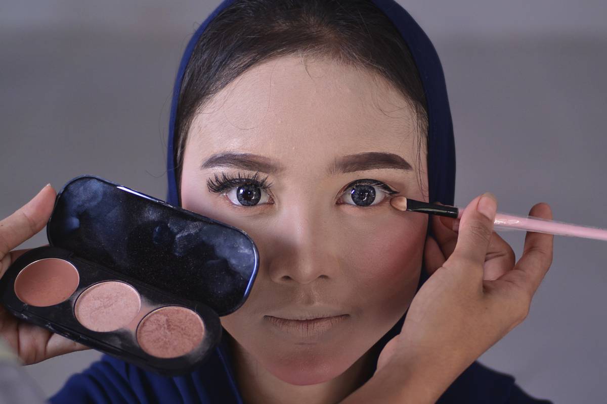 A woman applies face makeup.
