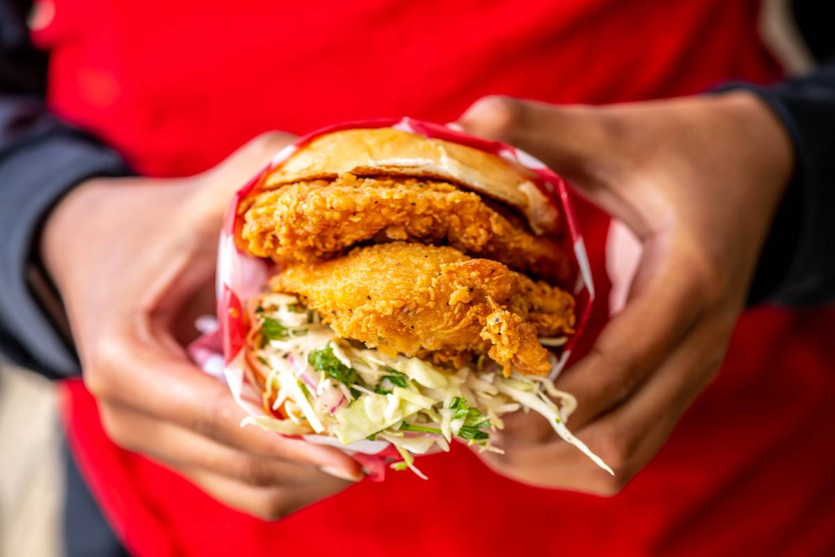 A person holds a fried chicken sandwich with slaw.