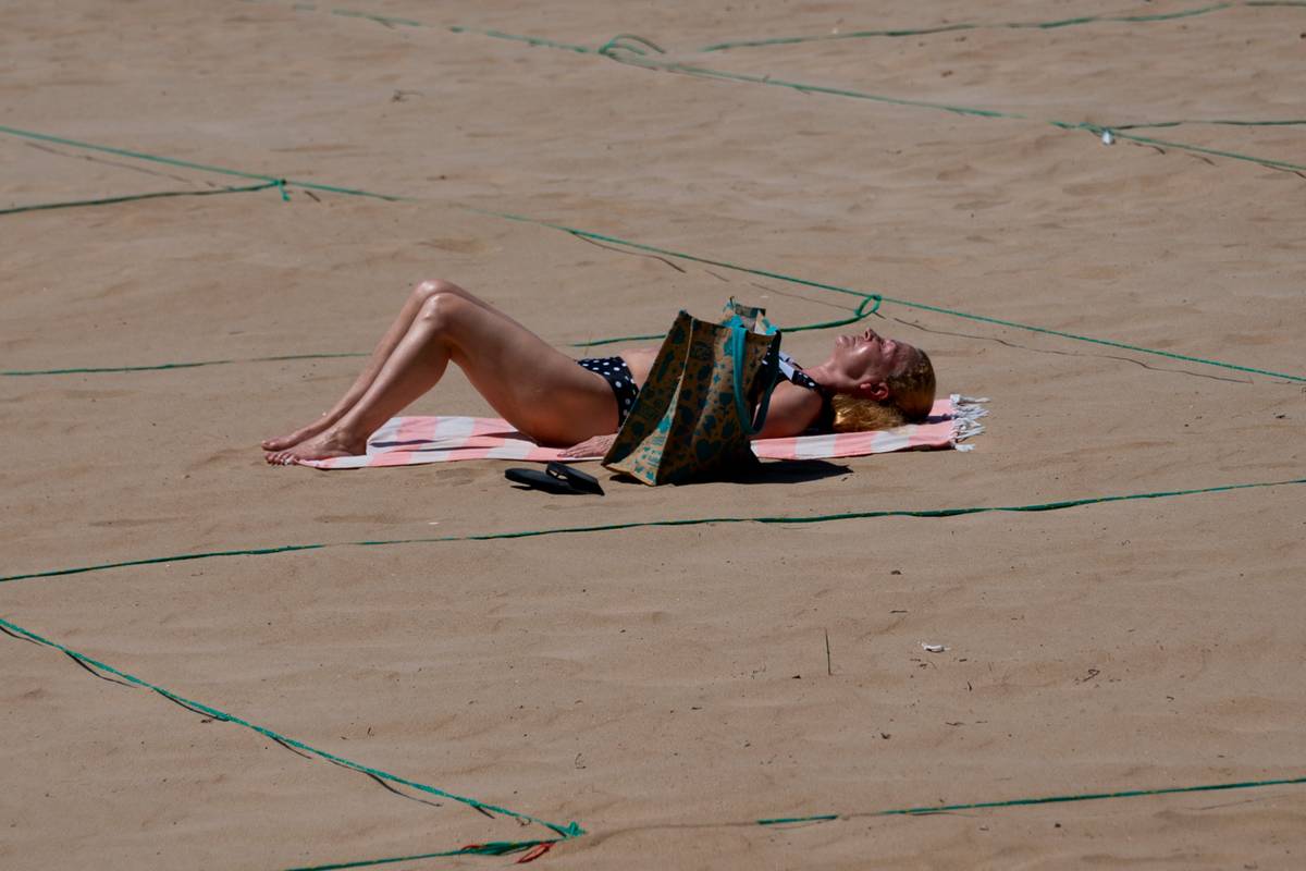 A woman tans on a beach.