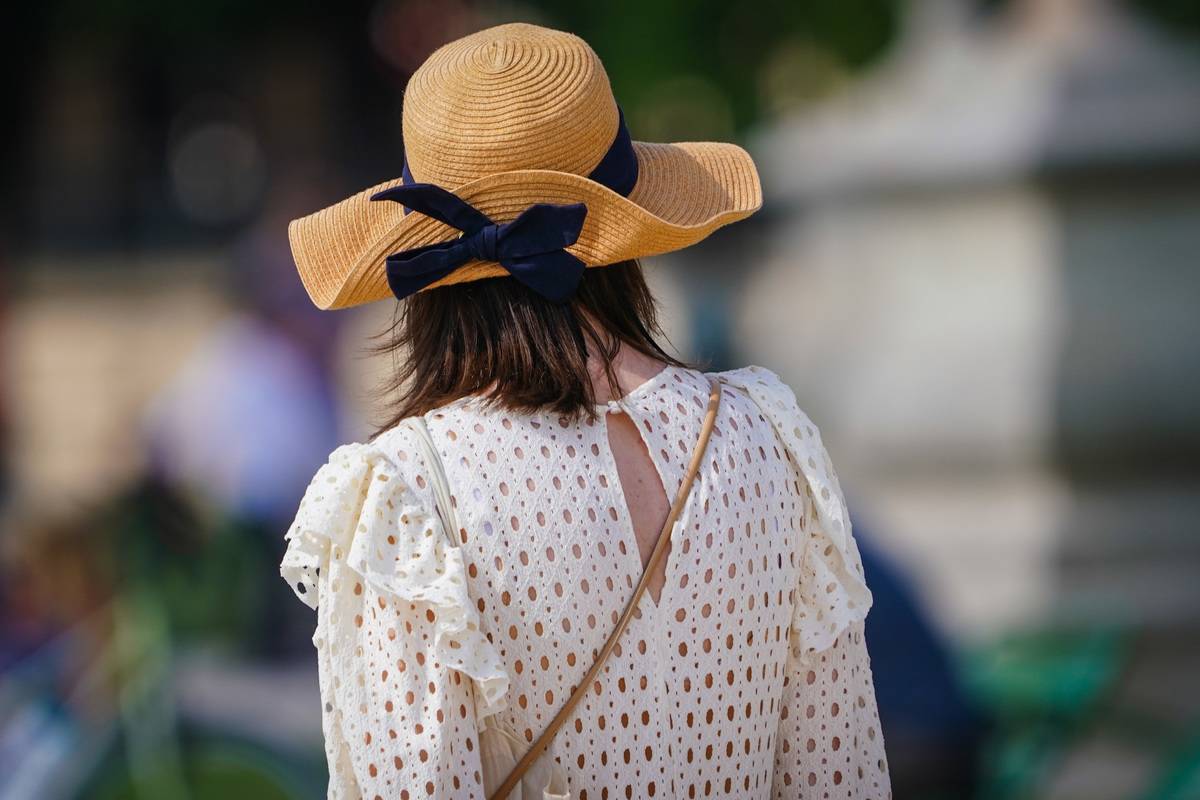 A woman wears a blouse and summer hat in Paris.