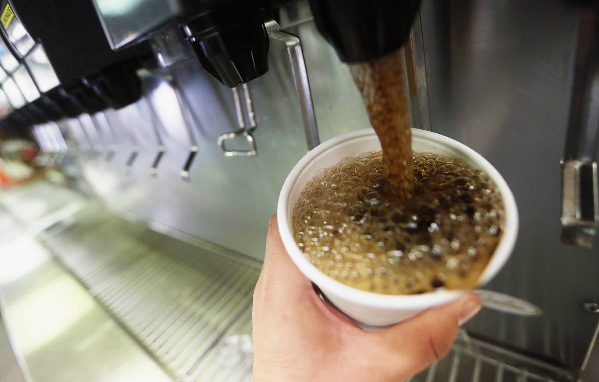 A customer pours soda into a cup with a machine at a McDonald's.