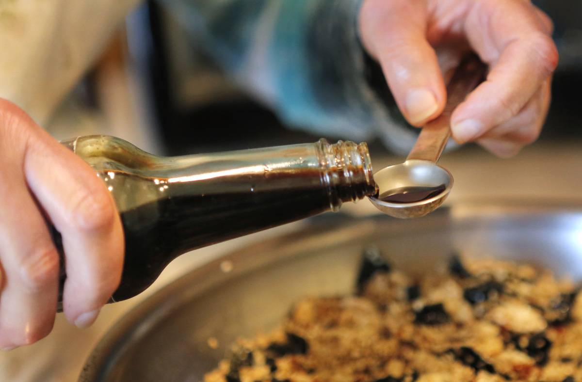 A chef portions soy sauce in a measuring spoon.