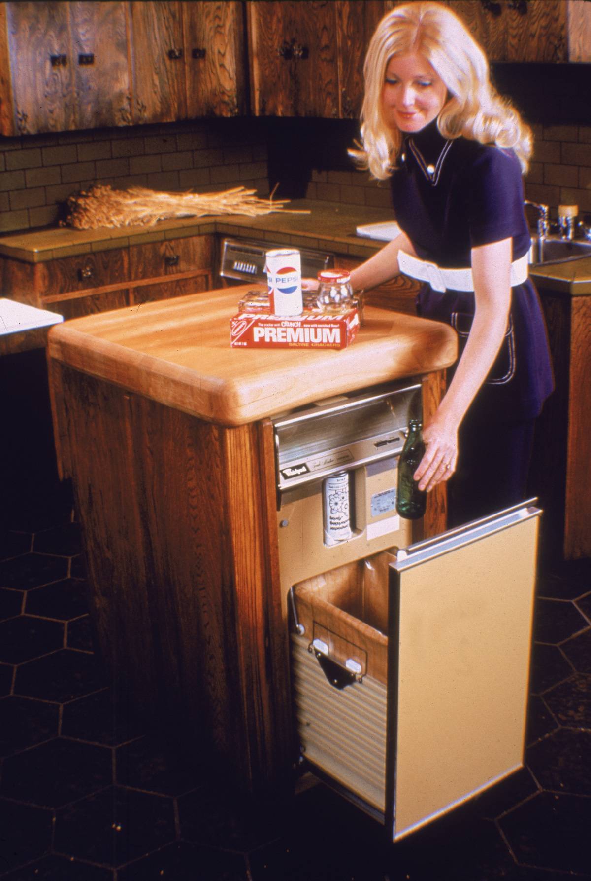 woman tosses waste into kitchen trash container