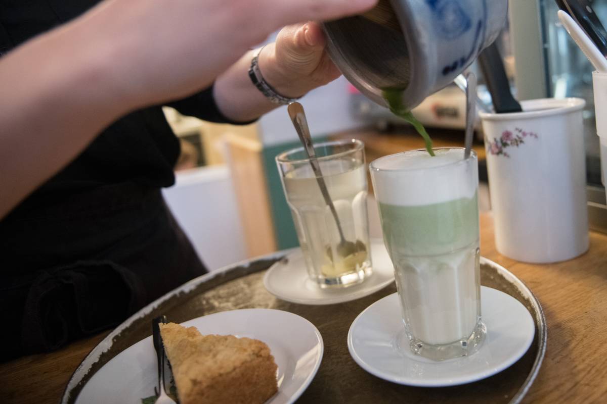A barista mixes a matcha latte at a cafe.