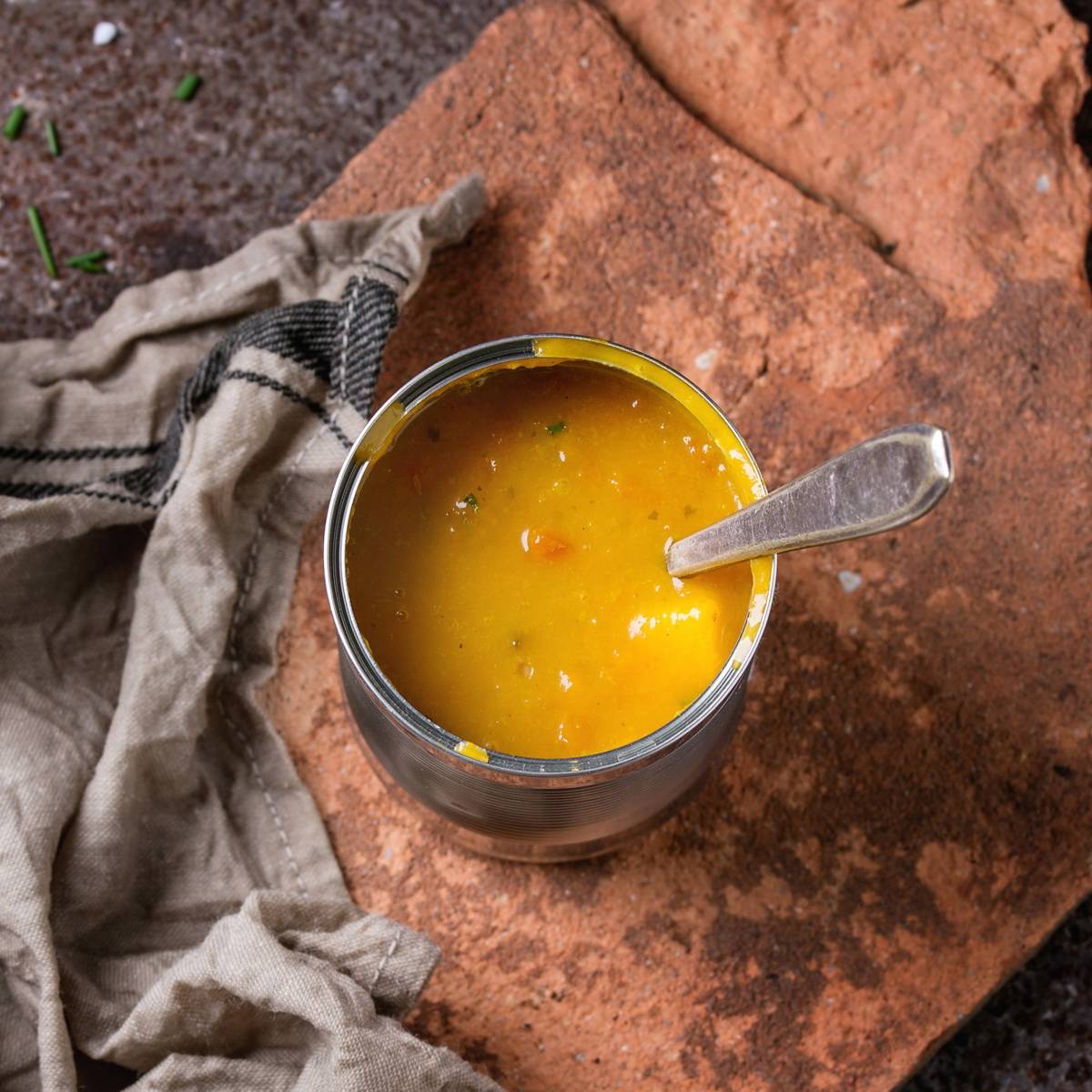 Tin can of carrot soup has a spoon in it.