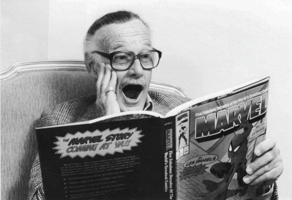 Comic book creator Stan Lee smiles while reading a book