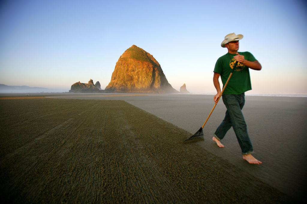 a barefoot cowboy walking on Cannon Beach in Oregon