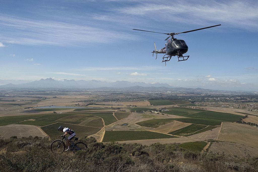 a helicopter flying near a cyclist in cape town, south africa