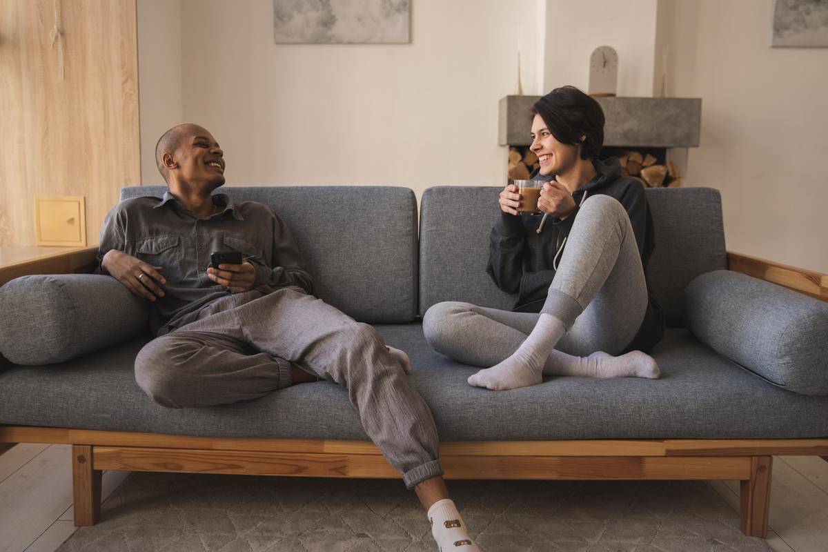 cheerful-young-diverse-couple-relaxing-on-couch-at-home