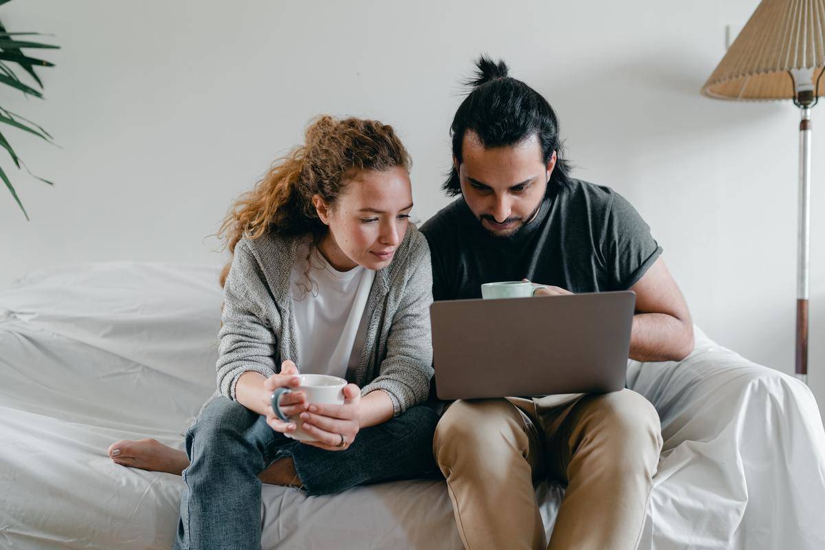 concentrated-couple-browsing-laptop-on-sofa