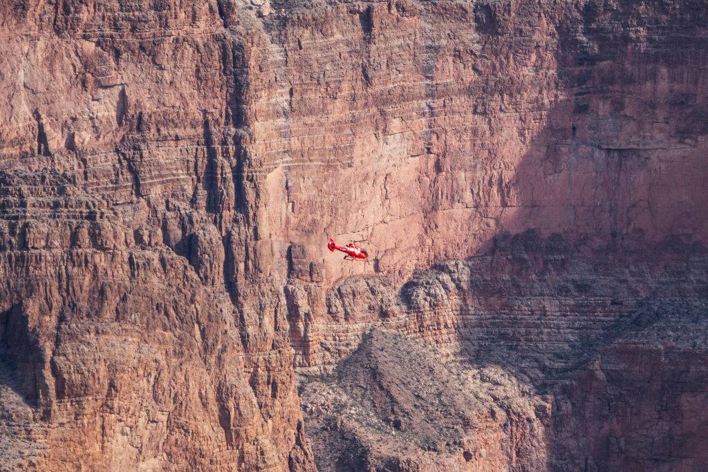 a red helicopter flying inside the grand canyon