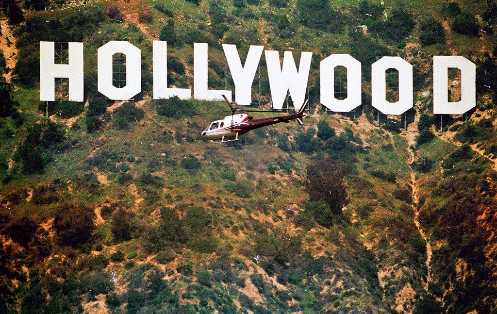 a helicopter flying in front of the hollywood sign