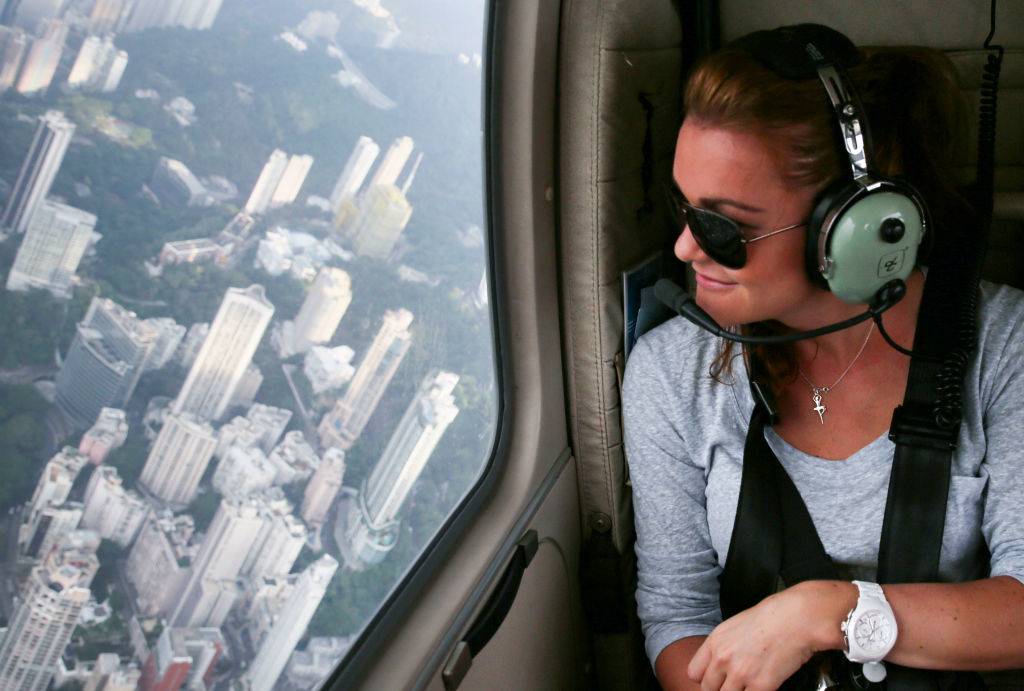 a girl flying in a helicopter over the skyscrapers in hong kong