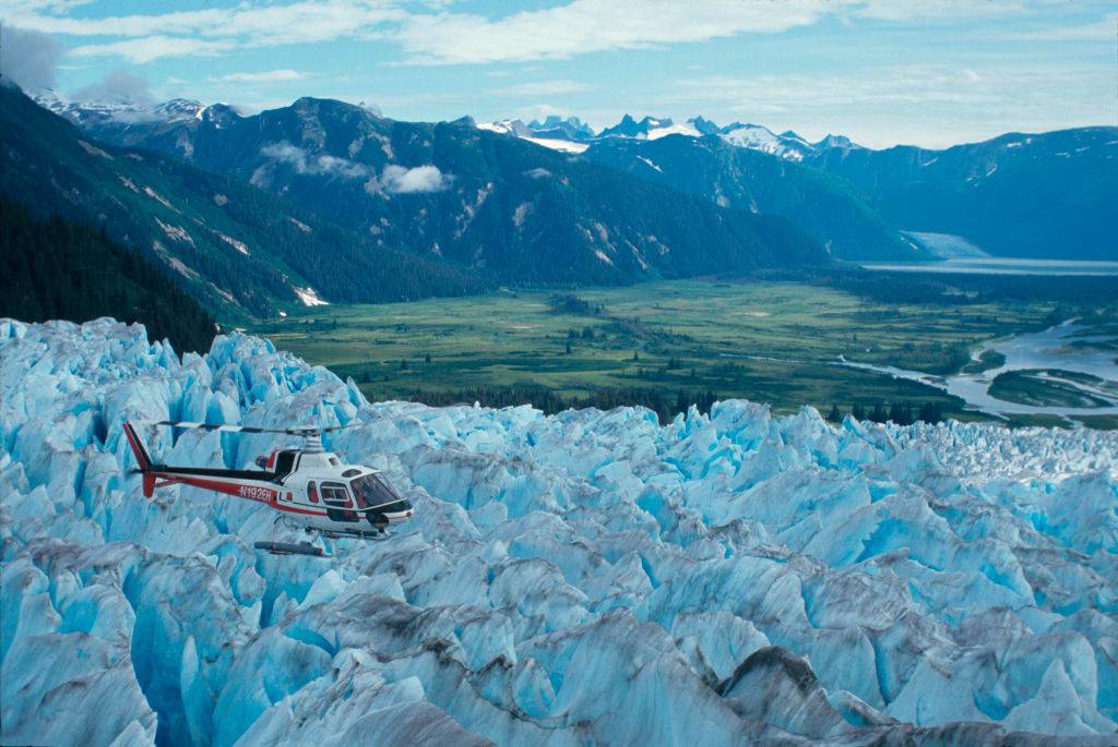 a helicopter flying over a glacier in juneau, alaska