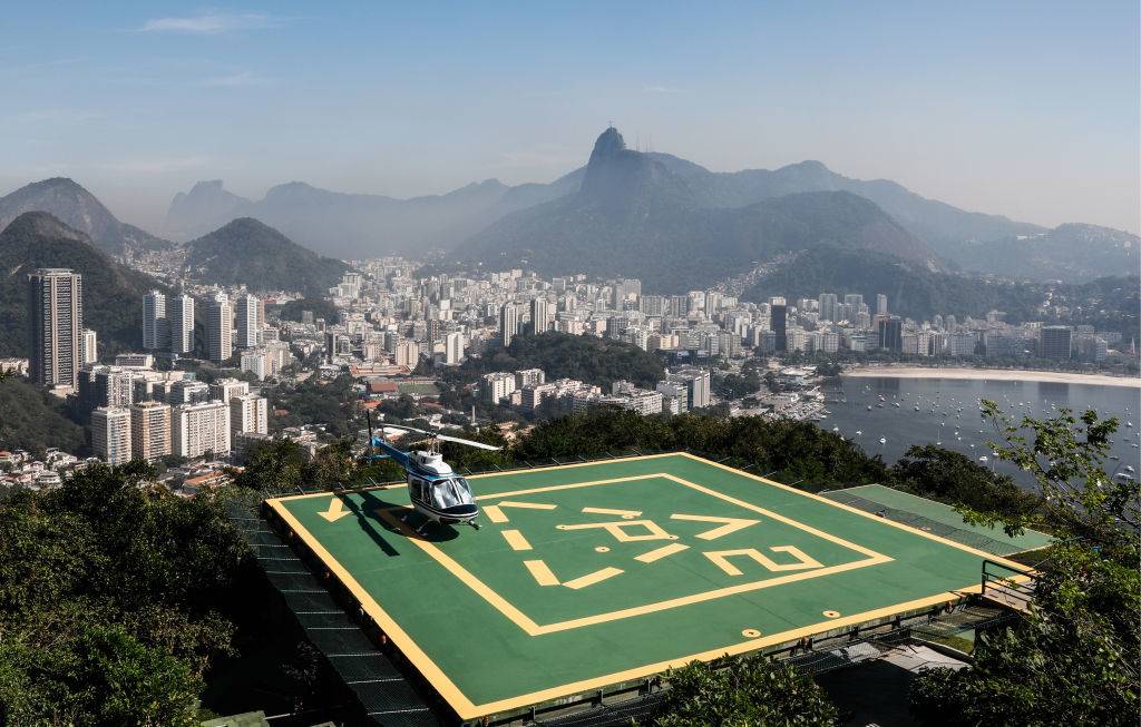 a helicopter on a launch pad atop the hills of rio de janeiro