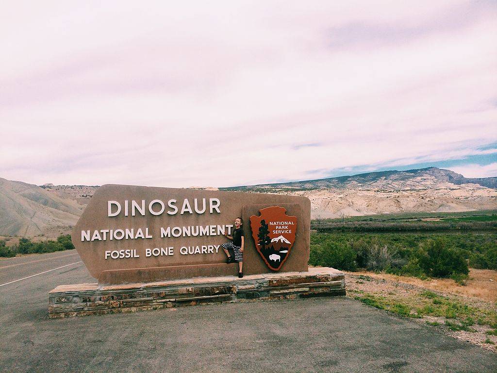 a boy standing in front of the Dinosaur National Monument sign in Vernal, Utah