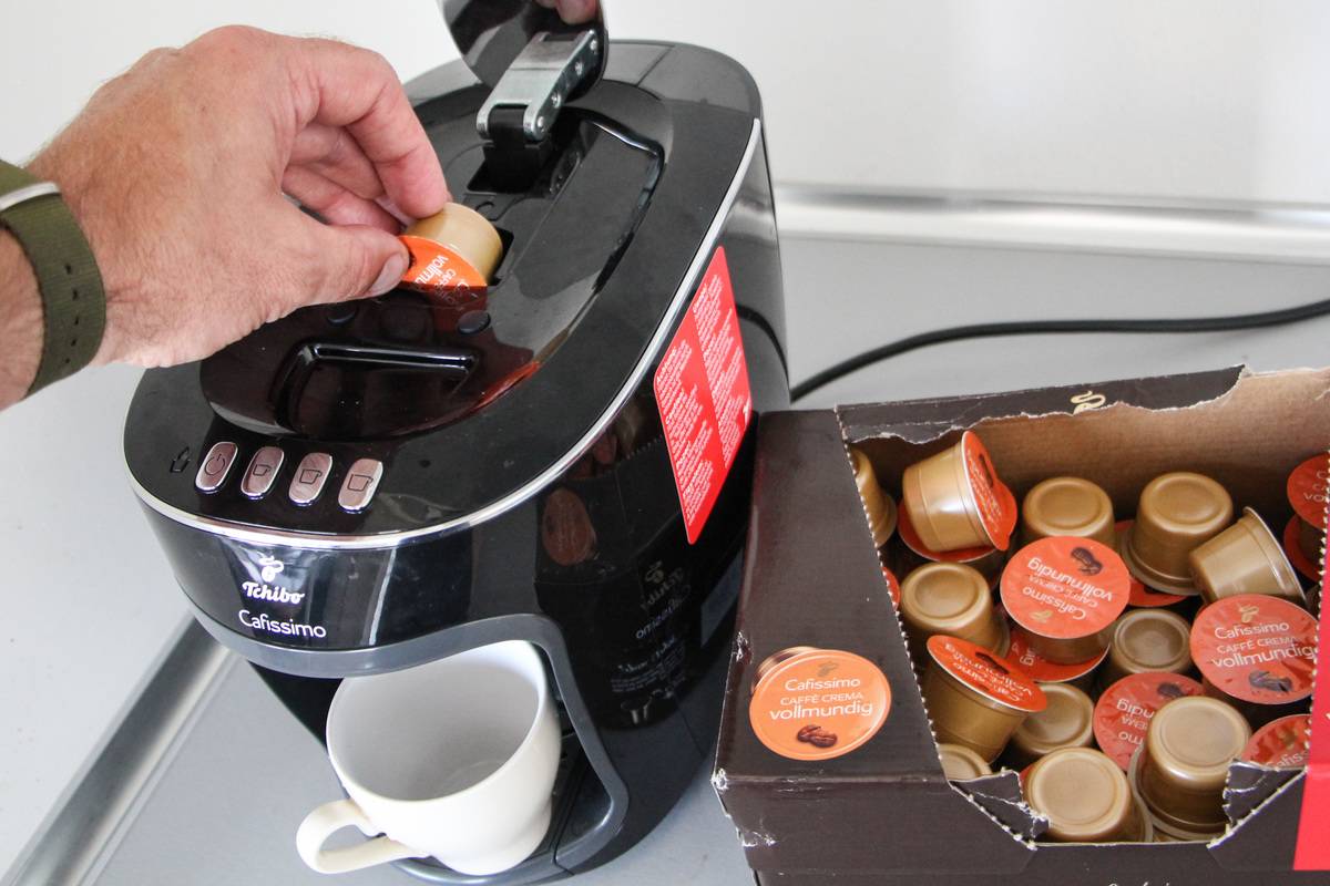 A person puts a capsule into a coffee machine.