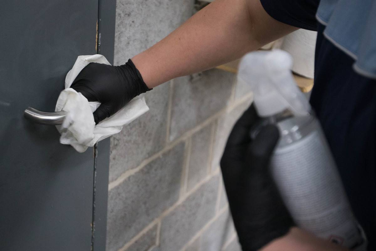 A man disinfects a doorknob with a wipe.
