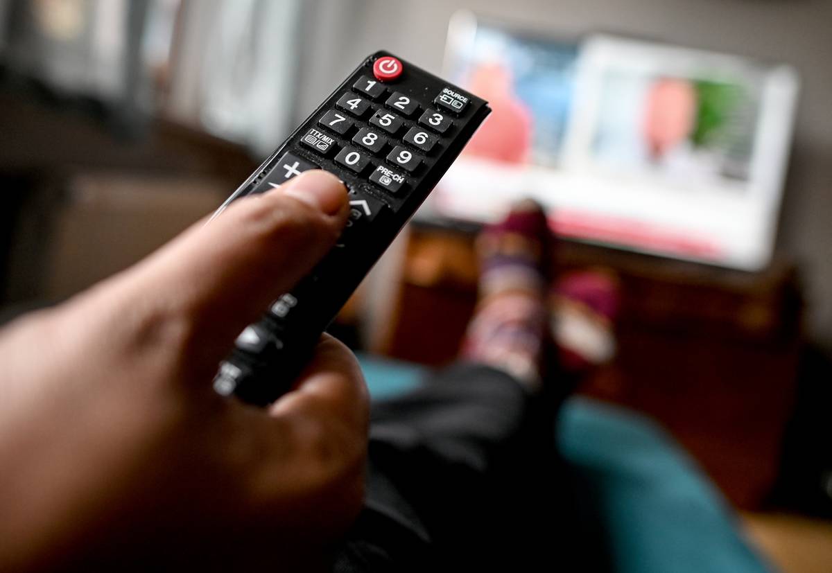 A person uses a remote while watching television.