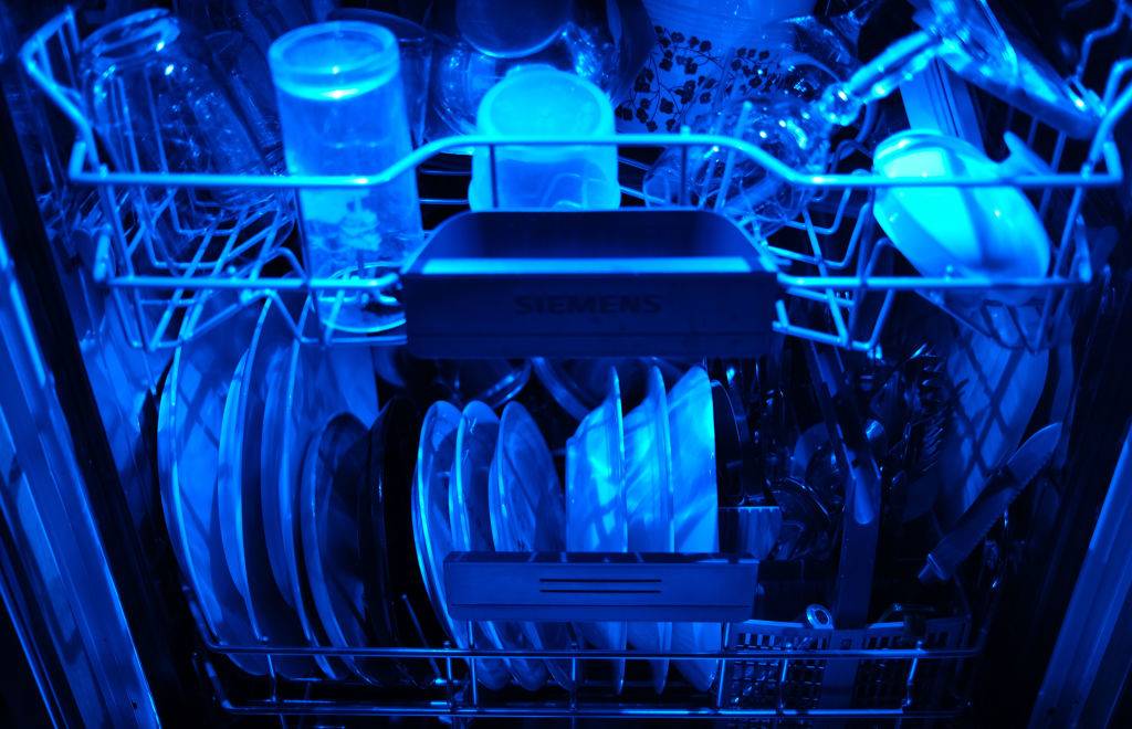 13 April 2020, North Rhine-Westphalia, Cologne: Washed dishes are in an open dishwasher with blue lighting. Photo: Oliver Berg/dpa