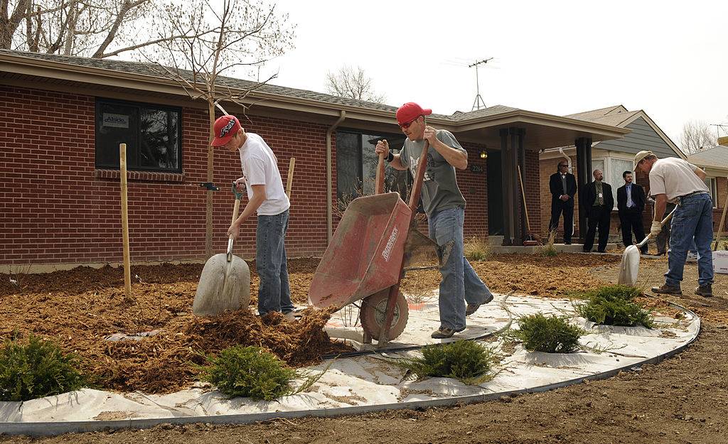 A landscaping crew from Prairie Snow Enterprises out of Keenesburg, CO, place mulch around new plants in front of a new HUD rehab home in Aurora
