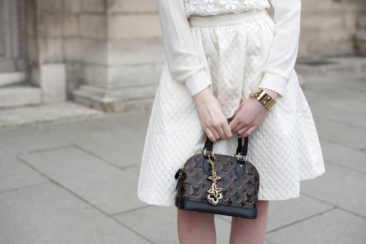 A fashion blogger holds a Louis Vuitton purse.