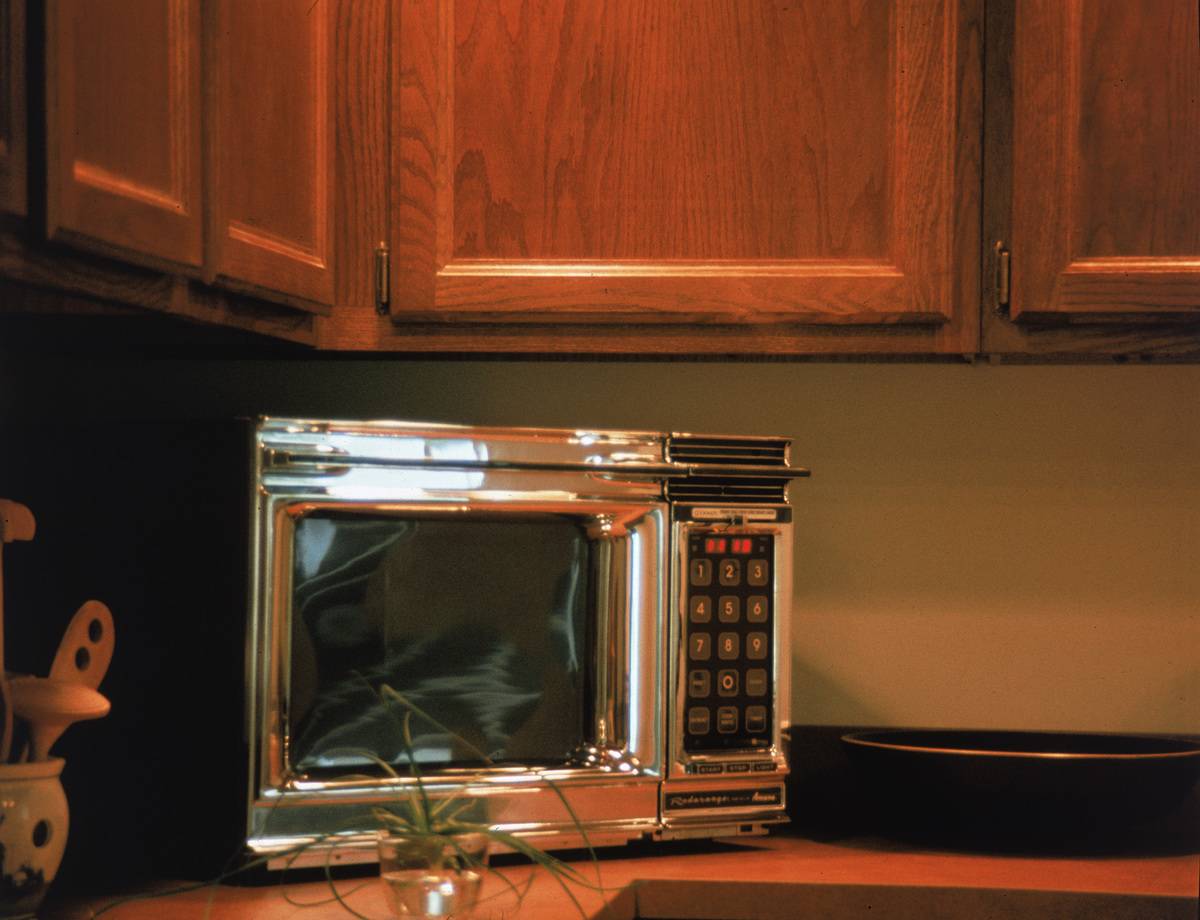 A chrome microwave sits on a kitchen counter.