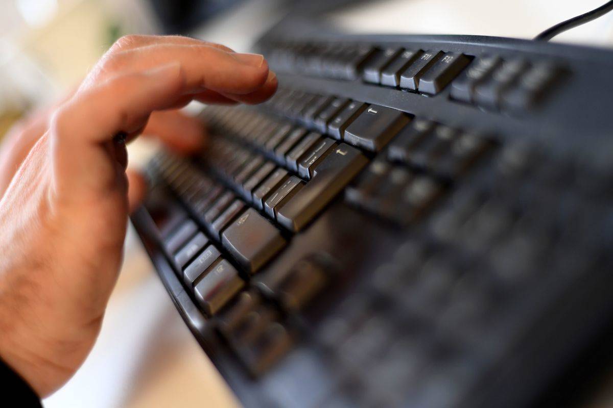 A person types on a computer keyboard.