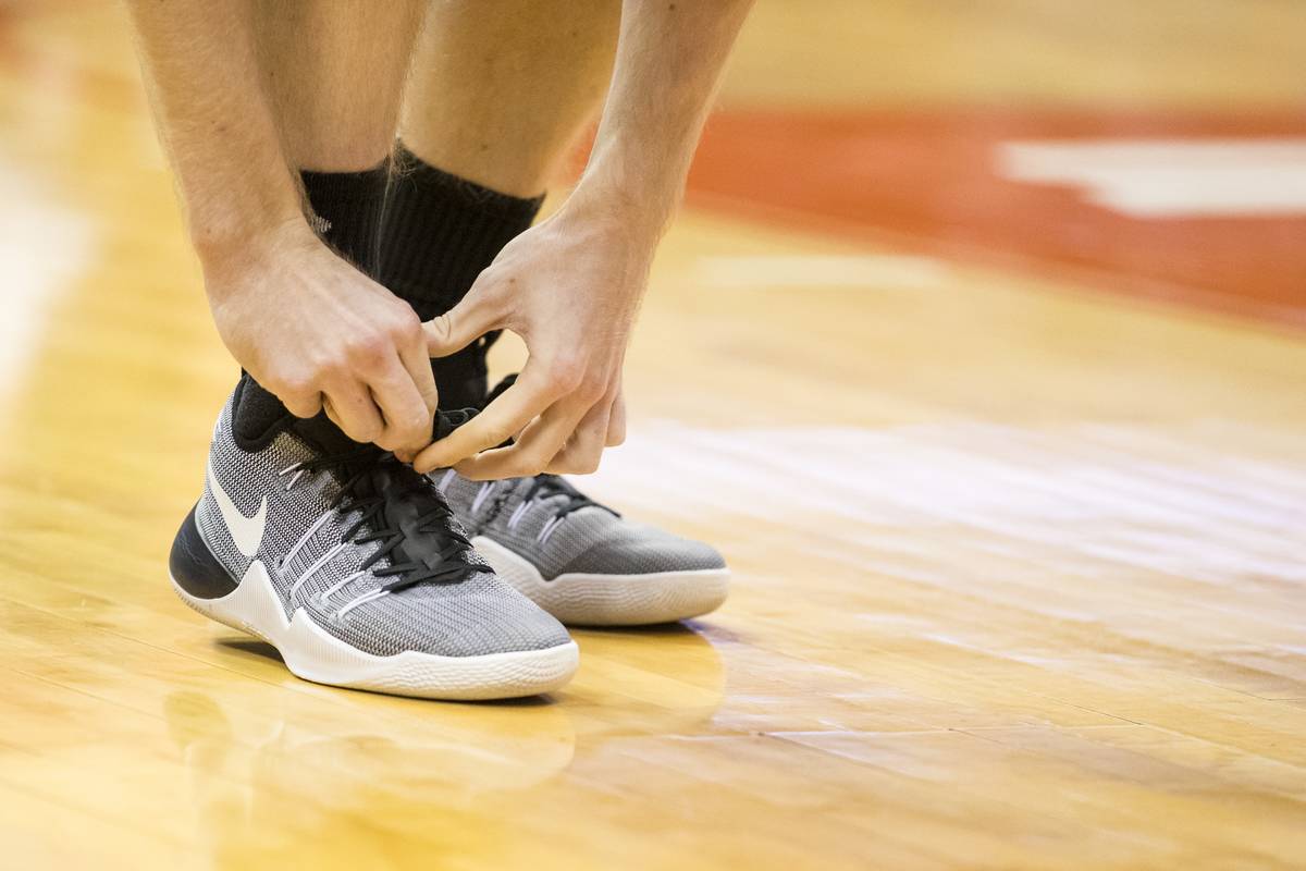 A basketball player ties his shoes.