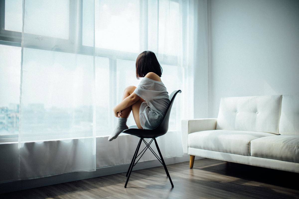woman sitting on chair looking out window