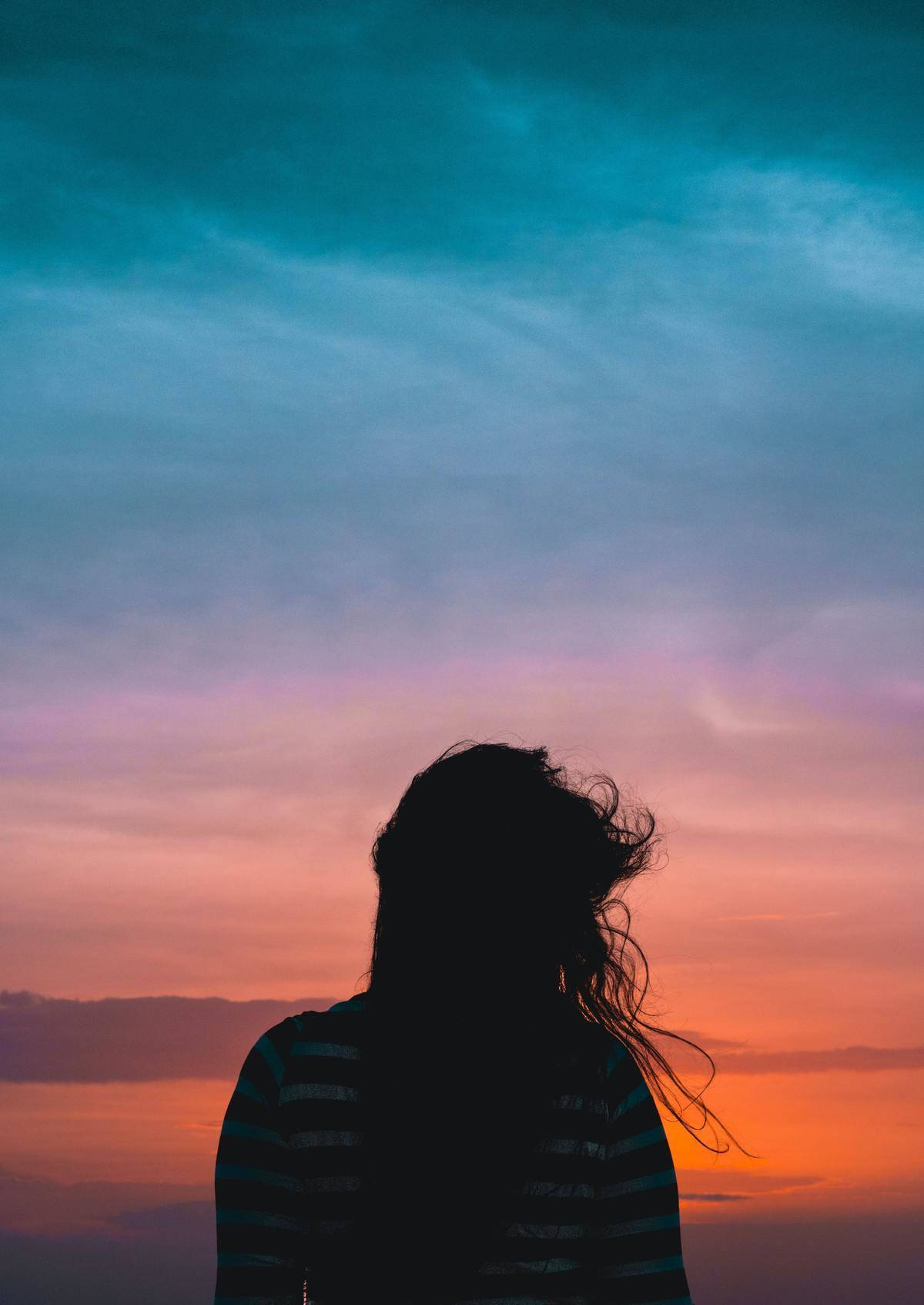 woman facing sunset with wind in hair