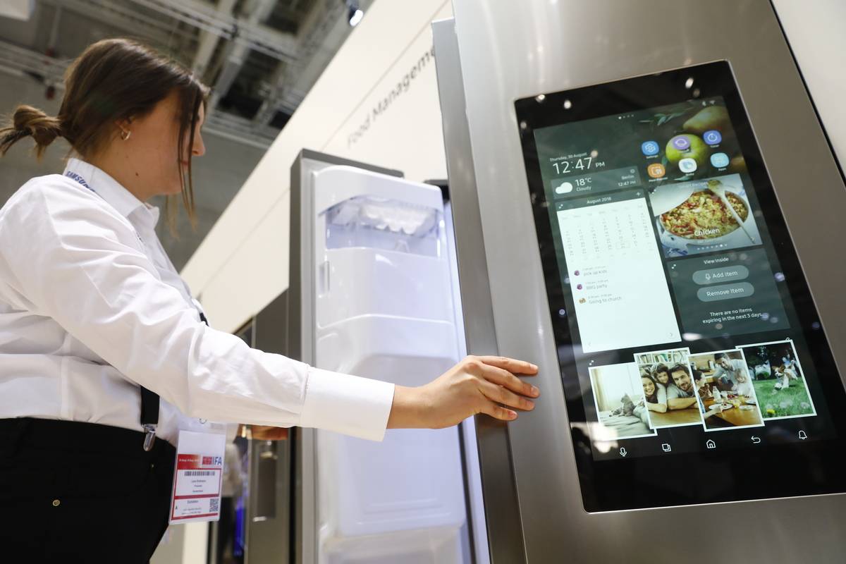 A woman opens a smart refrigerator.