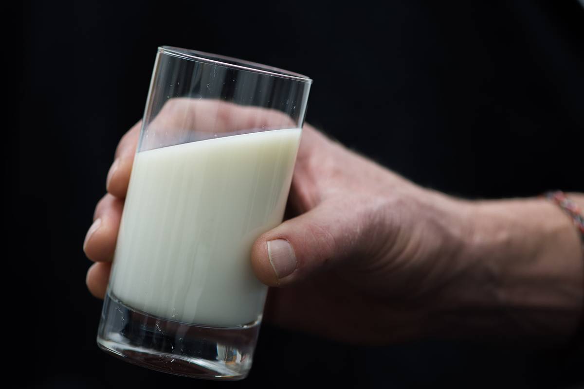 A person holds up a glass of milk.