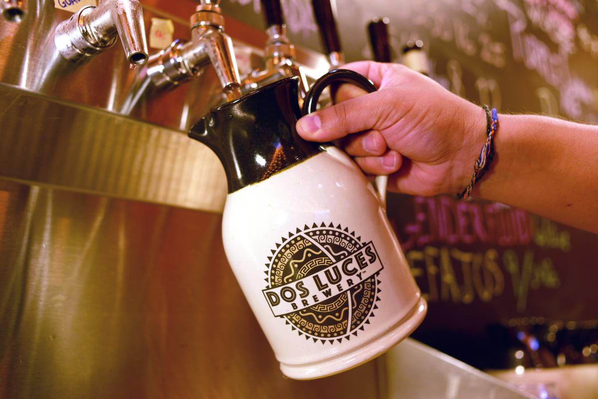 A customer pours chicha into a container at a brewery.