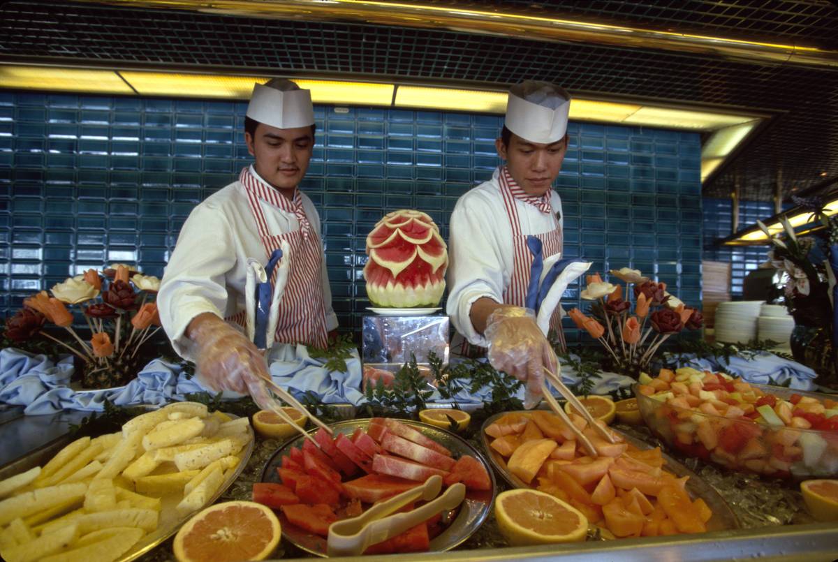 Chefs serve buffet style fruit on a cruise.