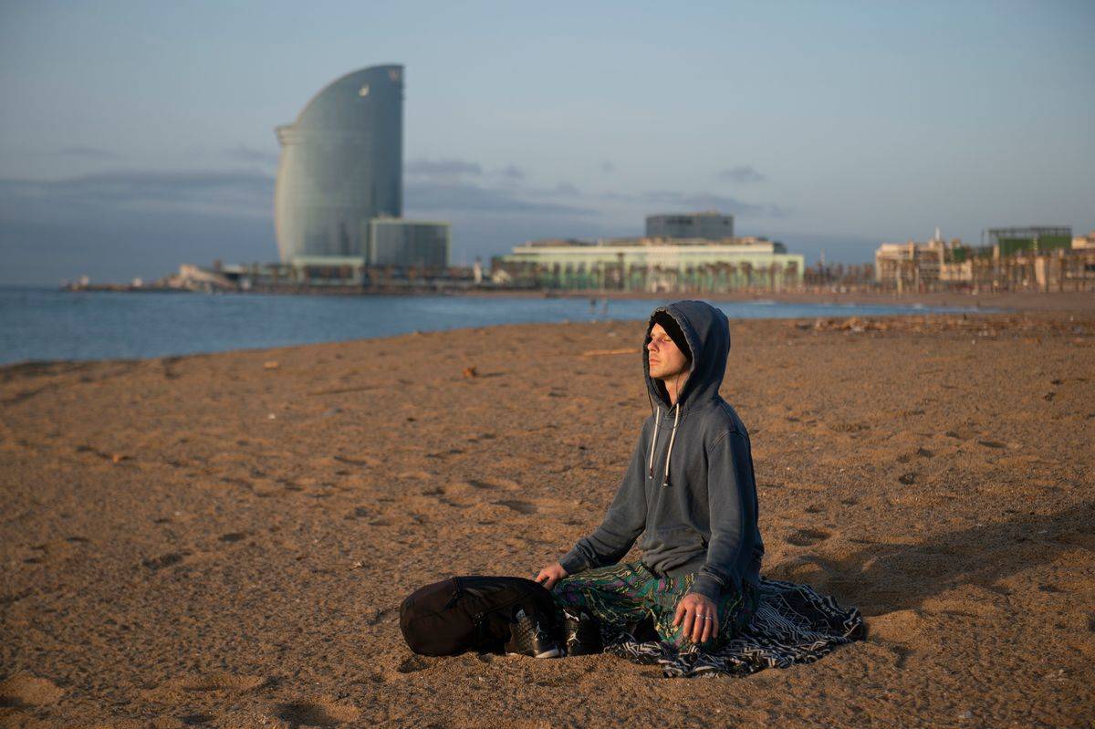 A man meditates as he parctices yoga at dawn at La Barceloneta Beach