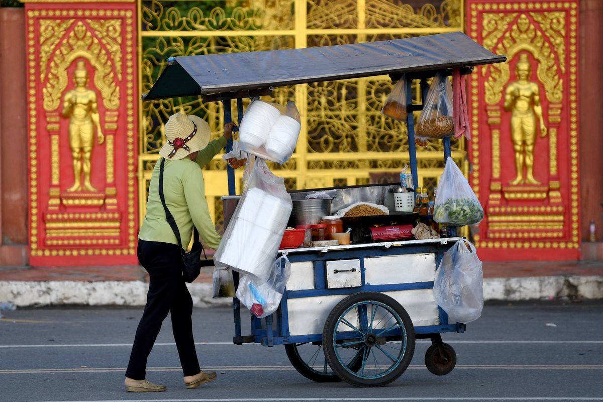 A vendor pushes a food cart across the street.