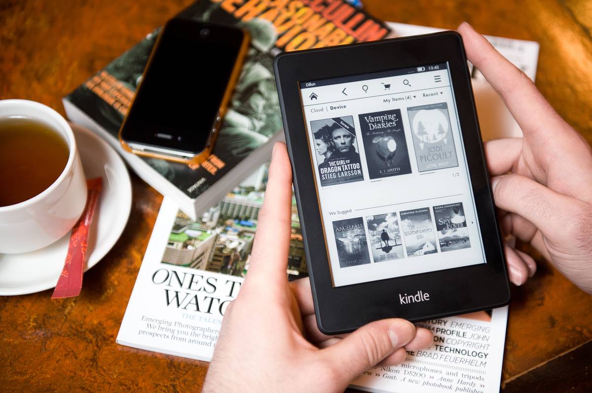 A person reads a Kindle Paperwhite at a cafe.