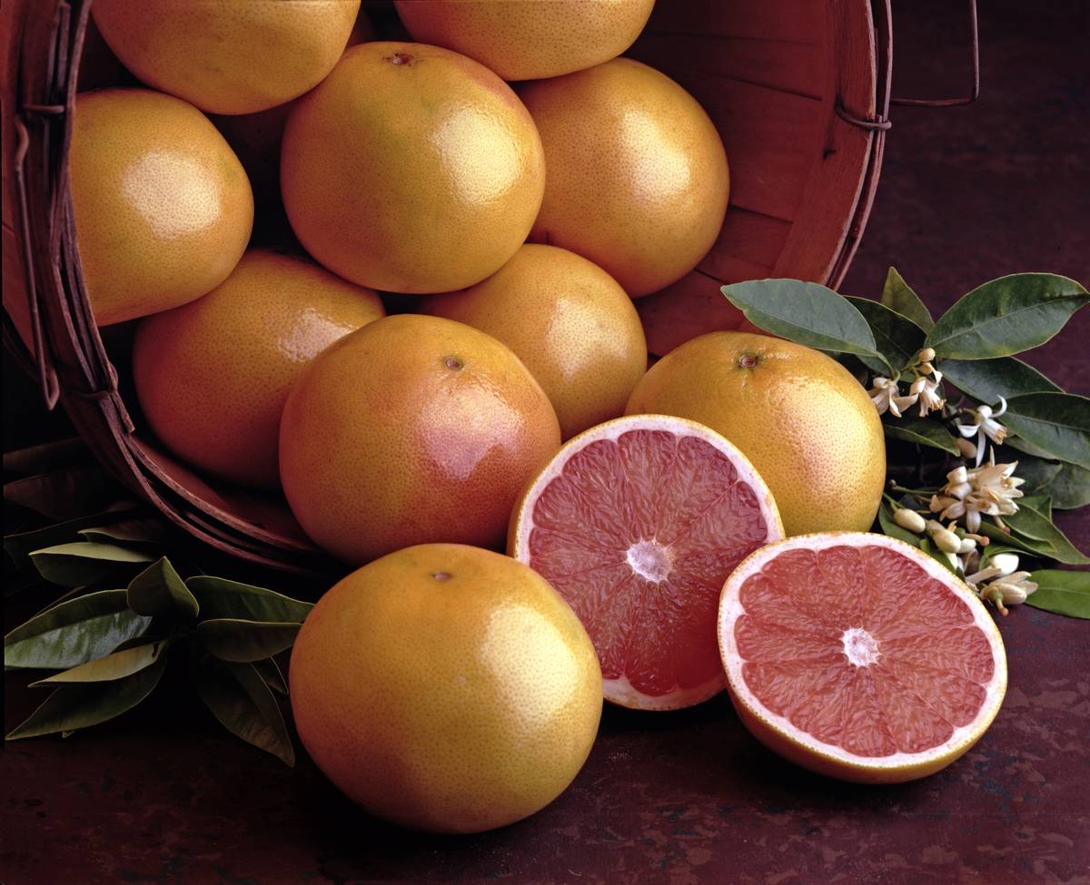 View of a basket of ruby red grapefruits, with one grapefruit cut in half