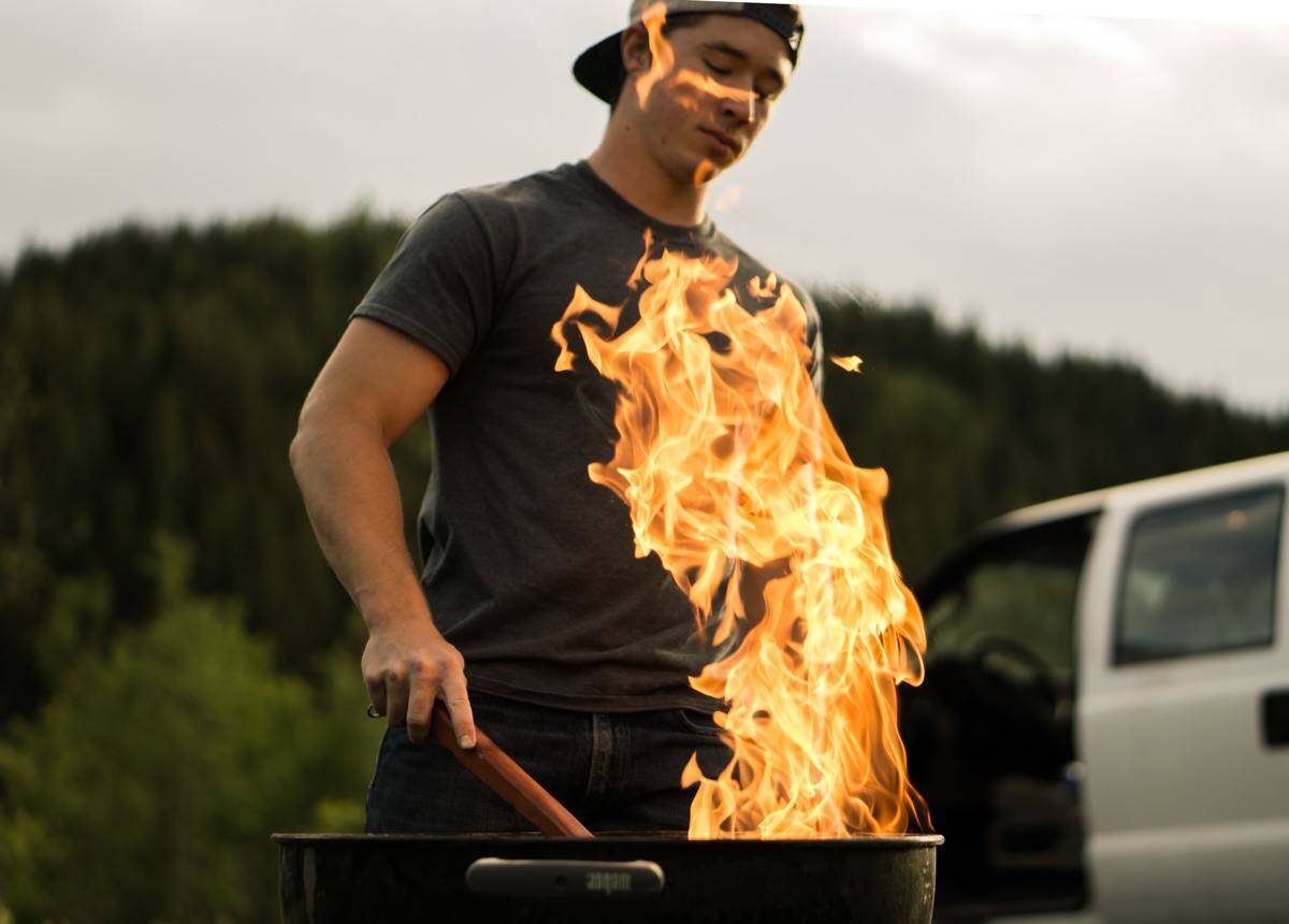 man cooks through fire on the grill