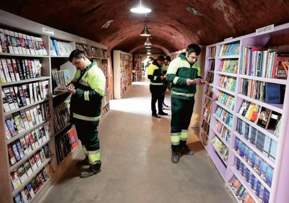 garbage collectors standing among shelves of books