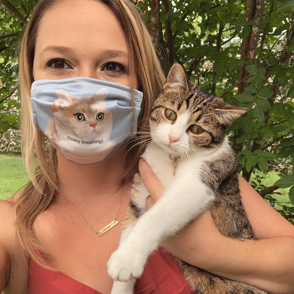 woman holds a cat while wearing a cat mask