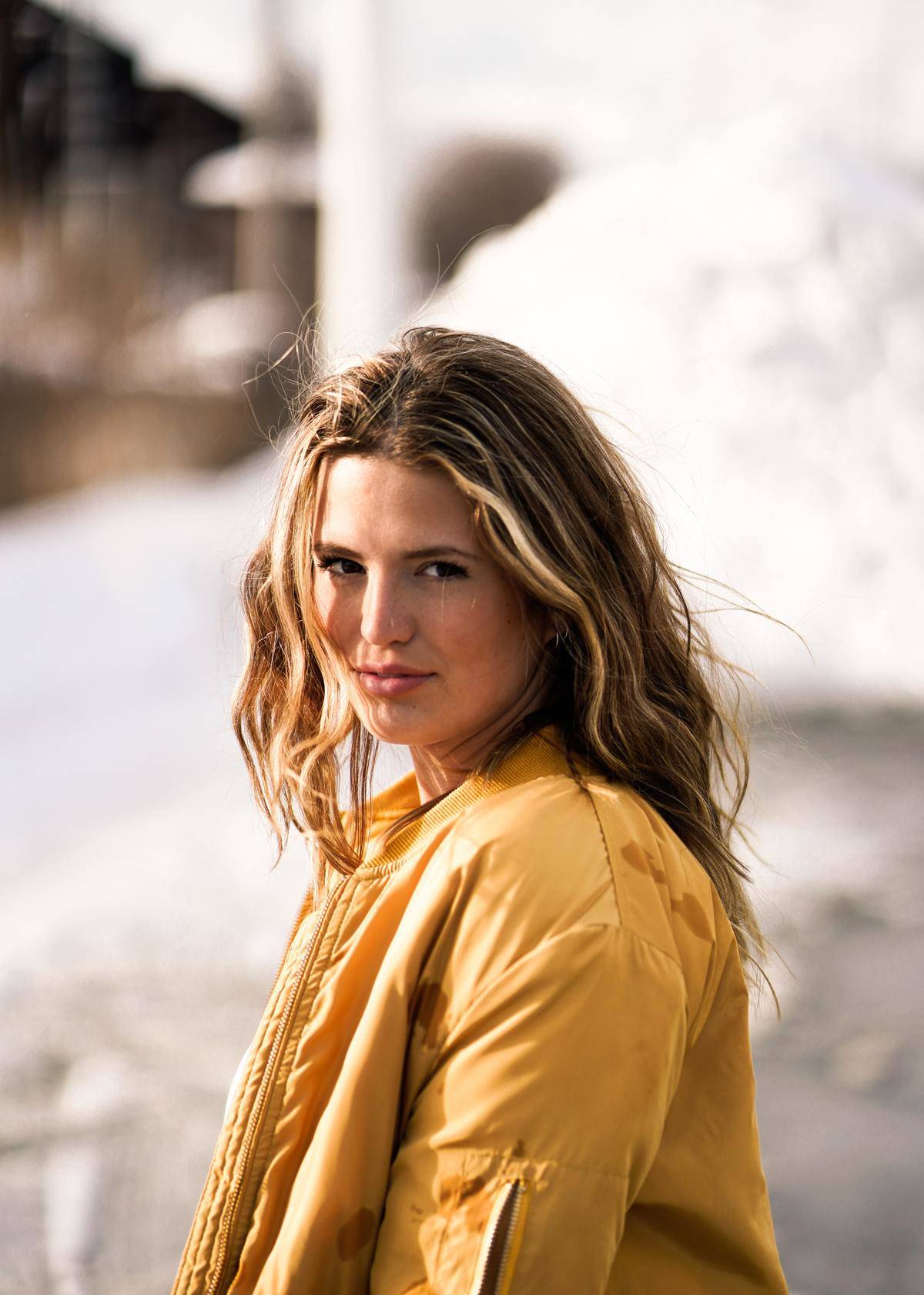 woman looks over and smiles in yellow coat